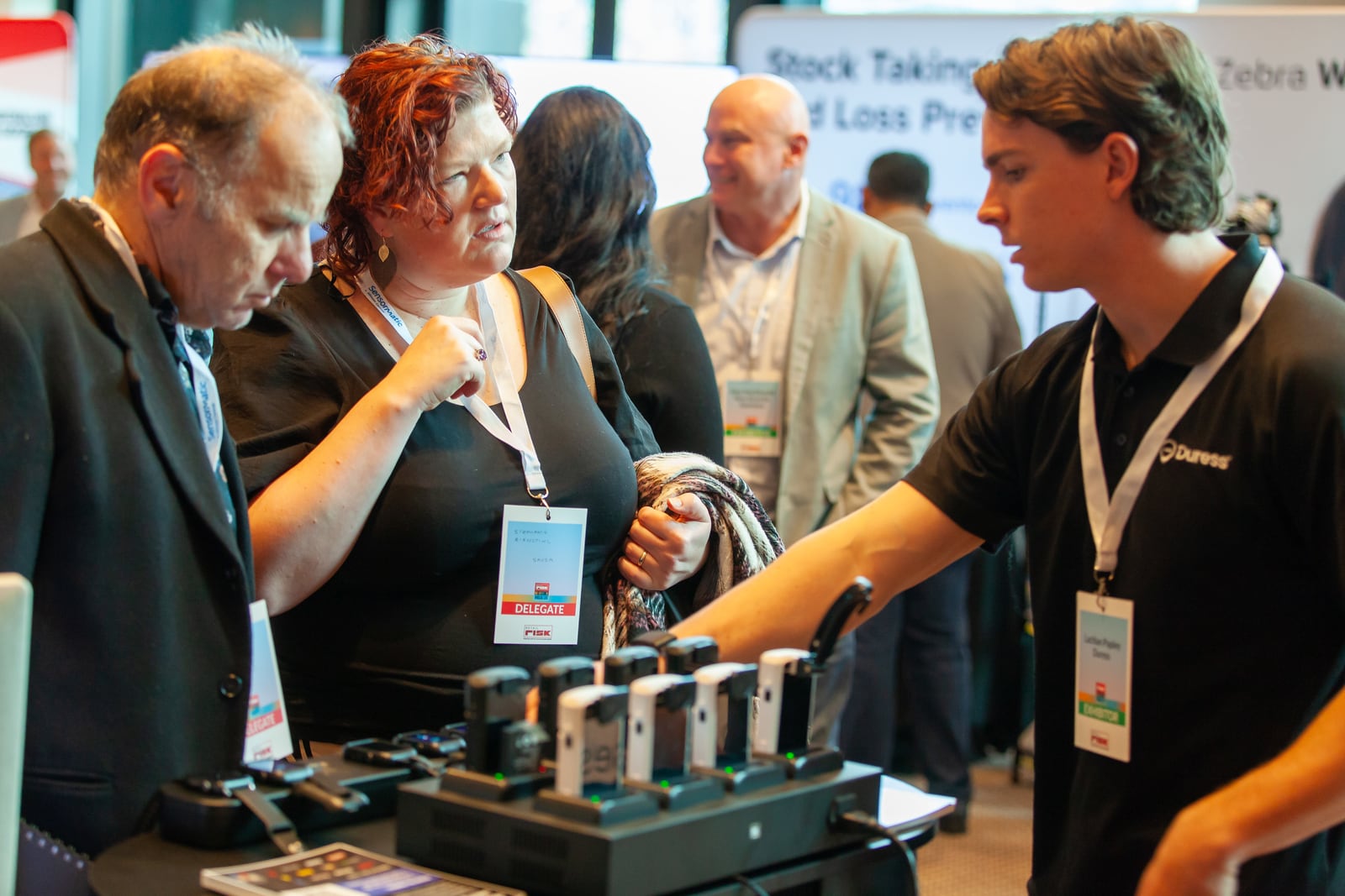A Duress team member demonstrating devices to delegates at the Duress stand, Retail Risk Melbourne 2025